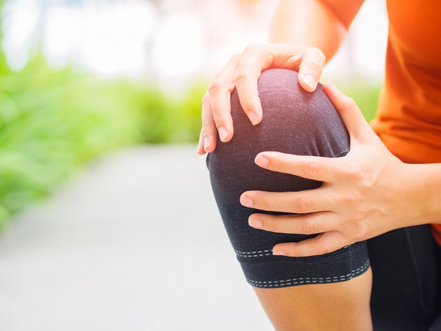 Runner sport knee injury. Woman in pain while running in the garden.
